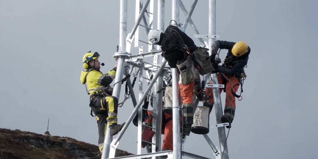 Engineers climbing high on phone mast to build it