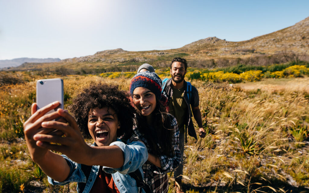 Group of four young people walking in a line in the countryside taking a selfie
